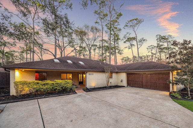 ranch-style home featuring a garage, driveway, and brick siding