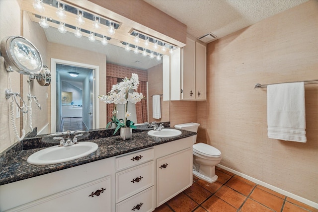 bathroom featuring toilet, a textured ceiling, visible vents, and a sink