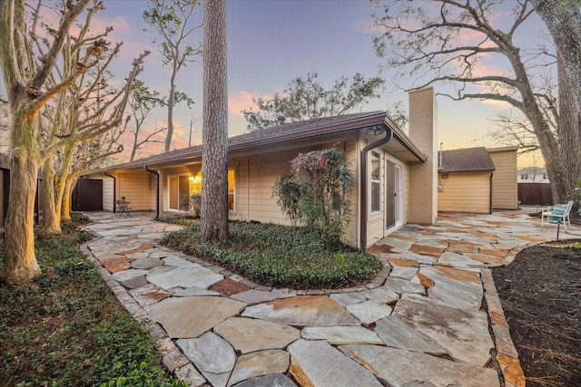 exterior space featuring a patio area, a chimney, and fence