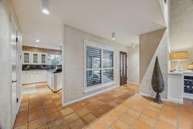 interior space featuring a textured wall, baseboards, and light tile patterned floors