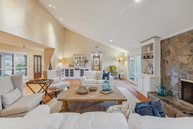 living area featuring high vaulted ceiling and a stone fireplace