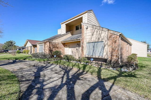 exterior space featuring brick siding and a front lawn