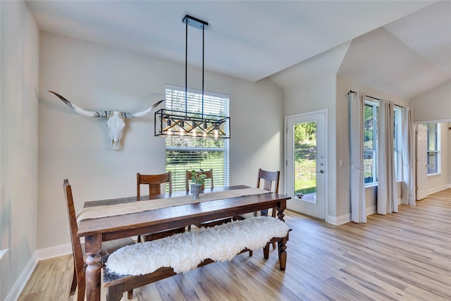 dining room featuring vaulted ceiling, light wood finished floors, and baseboards