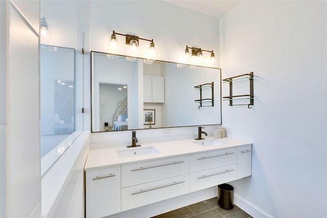 ensuite bathroom with double vanity, baseboards, a sink, and ensuite bathroom