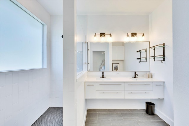 bathroom with double vanity, baseboards, a walk in shower, and a sink