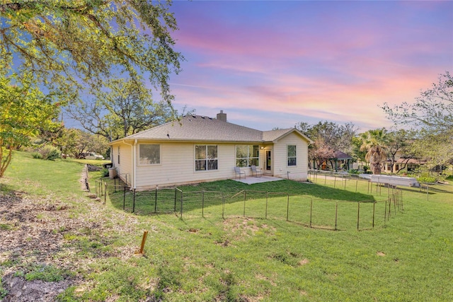 rear view of property with a chimney, fence, a patio, and a yard