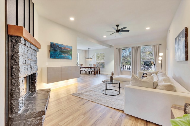 living room with recessed lighting, ceiling fan, a stone fireplace, wood finished floors, and baseboards