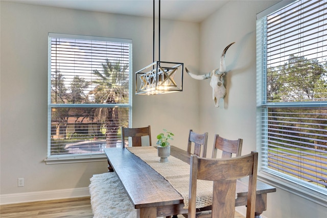 dining space with an inviting chandelier, baseboards, and wood finished floors