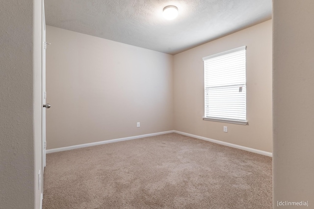 spare room with carpet, a textured ceiling, and baseboards