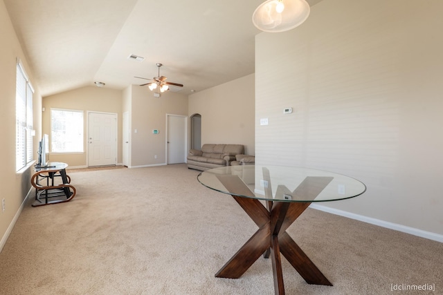 dining space featuring light carpet, baseboards, visible vents, arched walkways, and lofted ceiling