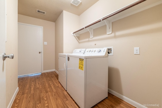 washroom with light wood-type flooring, laundry area, visible vents, and independent washer and dryer