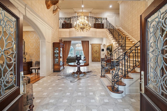 entrance foyer with wallpapered walls, a chandelier, arched walkways, and crown molding