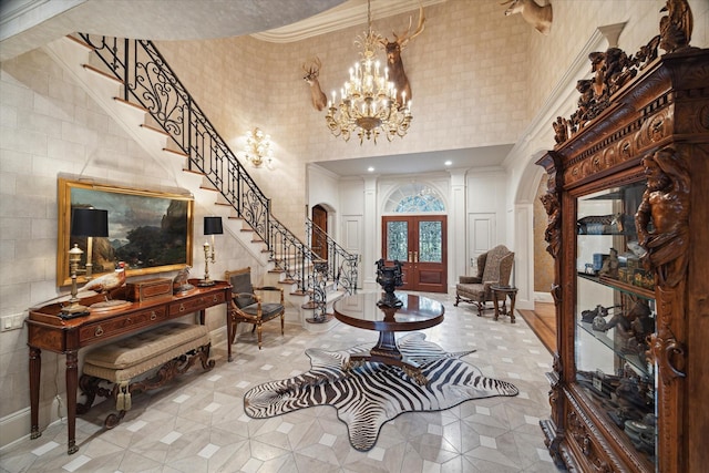 tiled entrance foyer featuring arched walkways, a towering ceiling, stairway, french doors, and a notable chandelier