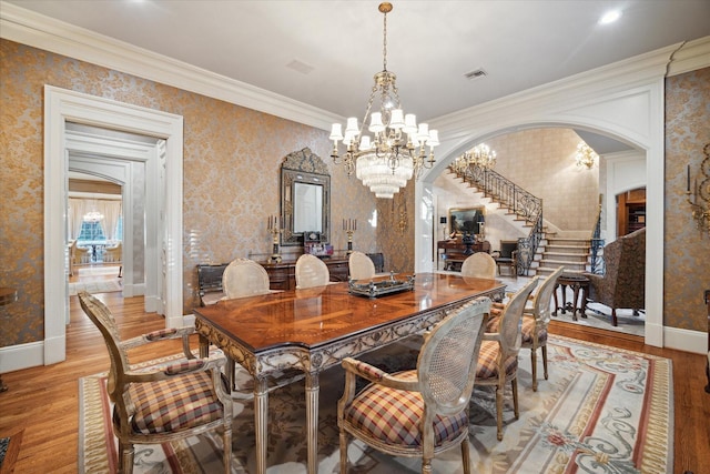 dining space featuring light wood-type flooring, arched walkways, and wallpapered walls