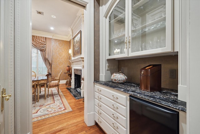 kitchen with glass insert cabinets, white cabinetry, visible vents, and crown molding