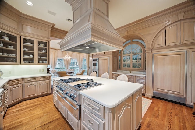 kitchen with custom range hood, a center island, light countertops, stovetop, and double oven