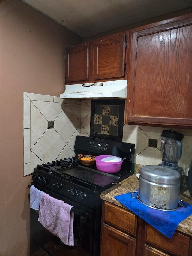 kitchen featuring tasteful backsplash, under cabinet range hood, and black gas range