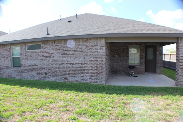 back of property with brick siding, a yard, and a patio