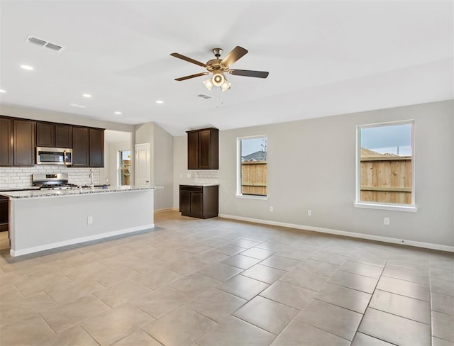 kitchen featuring stainless steel appliances, visible vents, decorative backsplash, open floor plan, and a sink