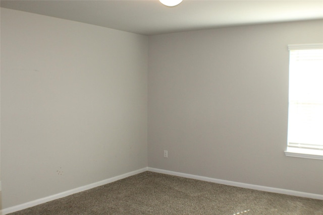 carpeted empty room featuring baseboards