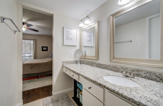 ensuite bathroom with ceiling fan, ensuite bathroom, wood finished floors, vanity, and baseboards