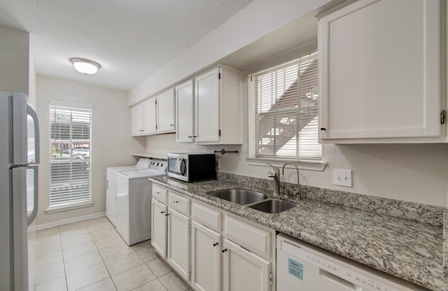 kitchen featuring stainless steel appliances, white cabinetry, a sink, light tile patterned flooring, and washer / dryer