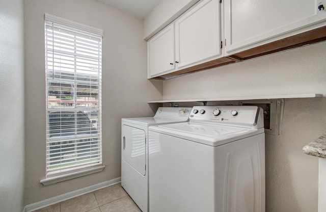 washroom featuring light tile patterned floors, washing machine and dryer, cabinet space, and baseboards