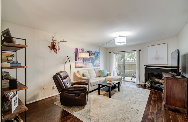 living area with a fireplace with flush hearth, baseboards, and hardwood / wood-style floors