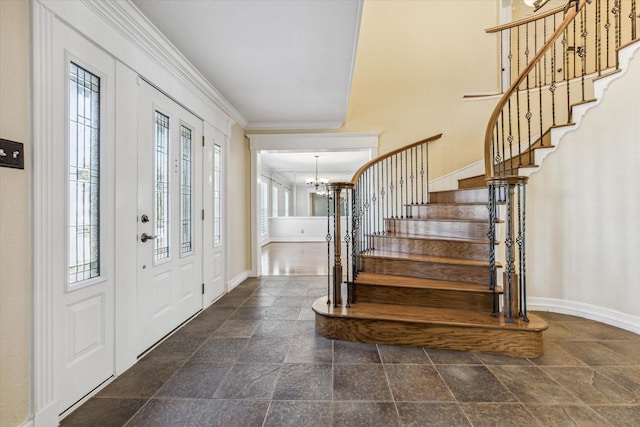 entryway featuring stone tile floors, baseboards, ornamental molding, stairs, and a chandelier