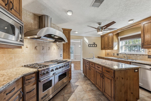 kitchen with a sink, stainless steel appliances, visible vents, and island range hood