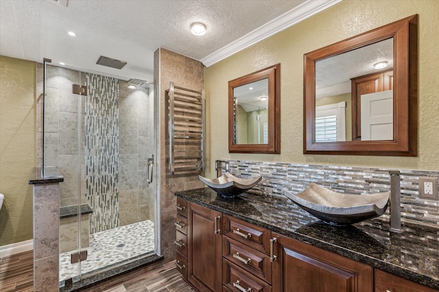 full bathroom with a shower stall, radiator heating unit, a textured wall, and a sink