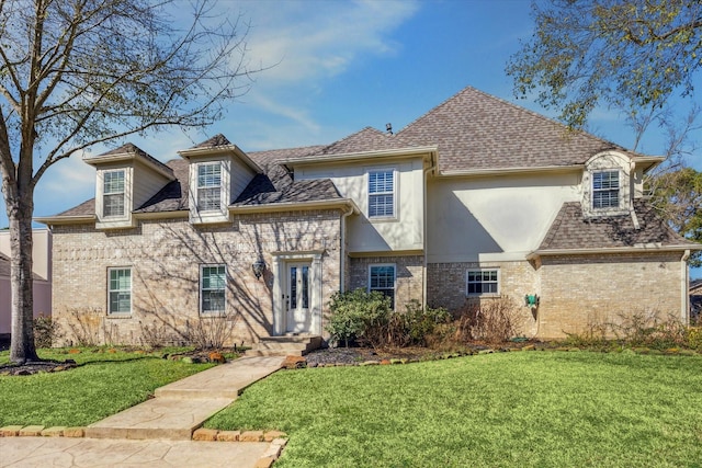 french country style house with brick siding, roof with shingles, and a front yard