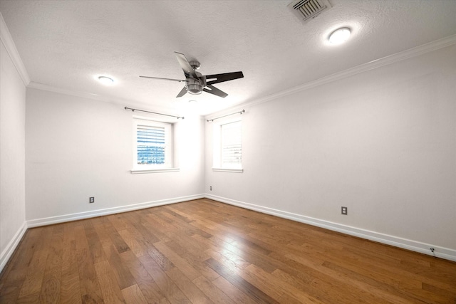 empty room with visible vents, crown molding, baseboards, wood finished floors, and a ceiling fan