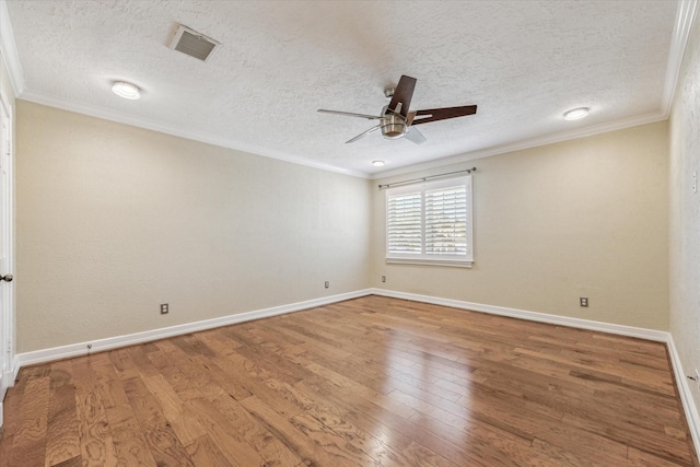 empty room featuring visible vents, ornamental molding, a ceiling fan, and wood finished floors