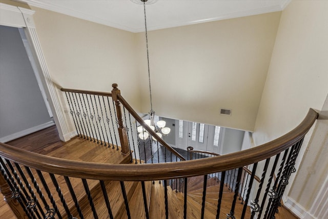 stairway featuring baseboards, wood finished floors, visible vents, and ornamental molding