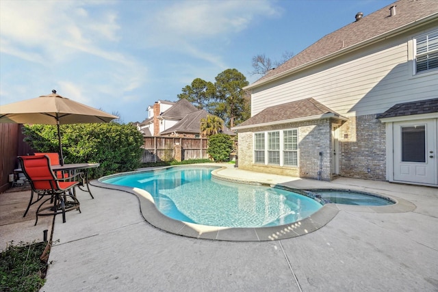 view of swimming pool with a pool with connected hot tub, a patio area, and a fenced backyard