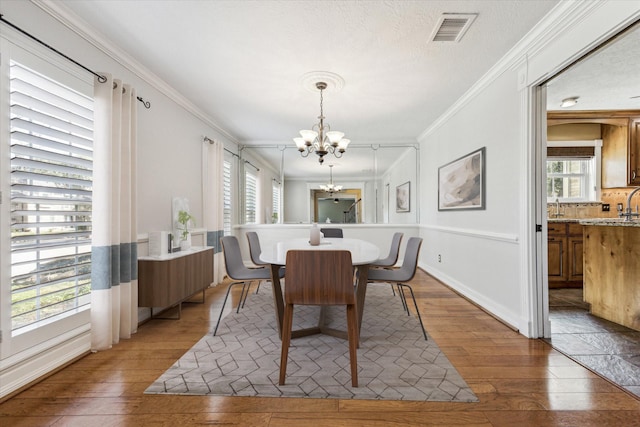 dining space with light wood-style floors, visible vents, a notable chandelier, and crown molding