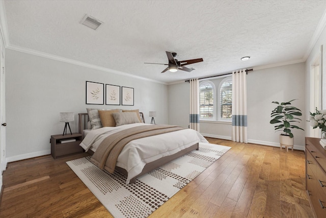 bedroom with light wood-type flooring, visible vents, ornamental molding, a textured ceiling, and baseboards