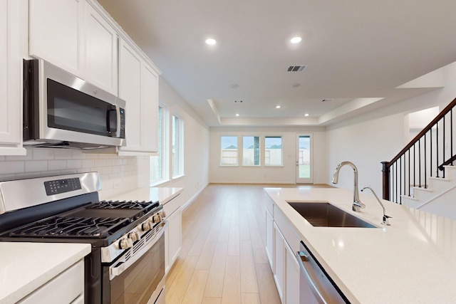 kitchen with visible vents, appliances with stainless steel finishes, a sink, light countertops, and backsplash