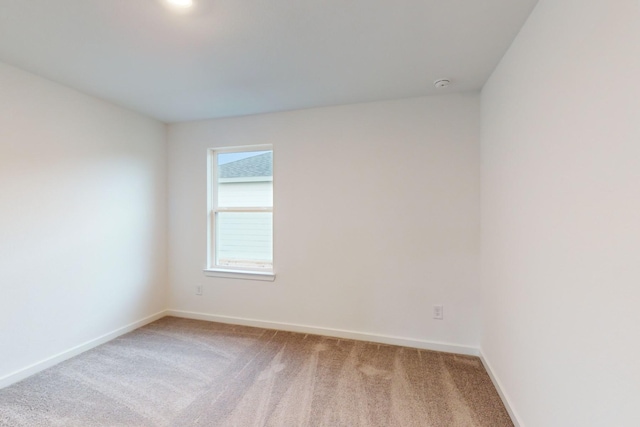 spare room with baseboards and light colored carpet