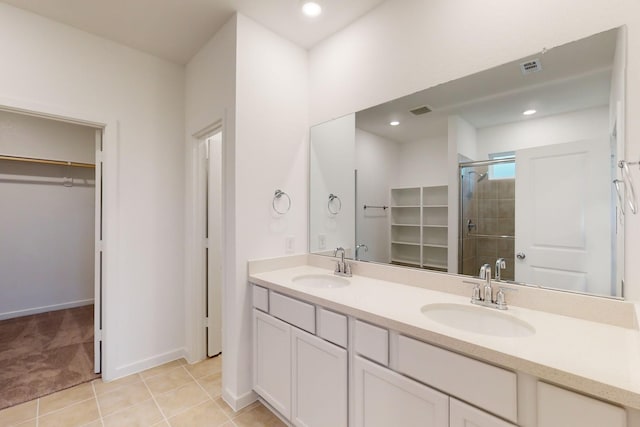 bathroom with a stall shower, a sink, a spacious closet, and double vanity