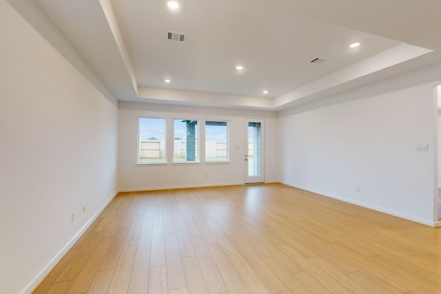 spare room featuring light wood-style flooring, visible vents, a raised ceiling, and recessed lighting