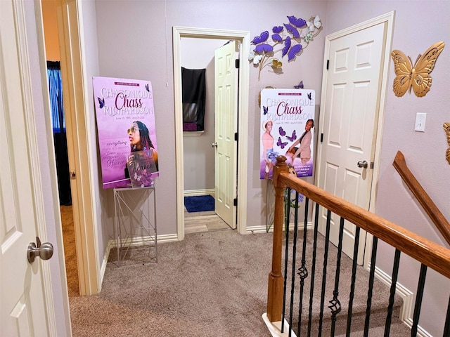 corridor with an upstairs landing, carpet flooring, and baseboards