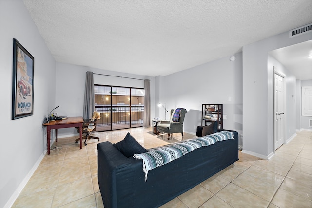 living area featuring light tile patterned floors, a textured ceiling, visible vents, and baseboards