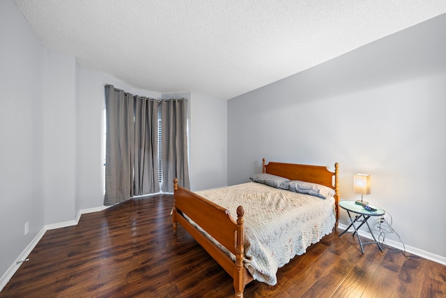 bedroom with a textured ceiling, baseboards, and wood finished floors