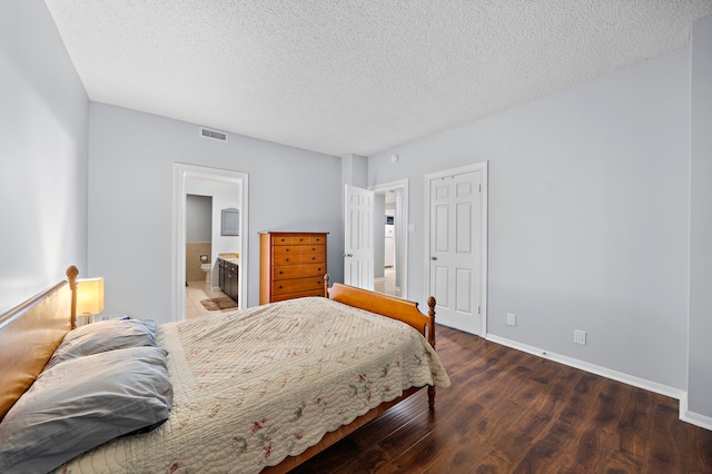 bedroom with a textured ceiling, wood finished floors, visible vents, and baseboards