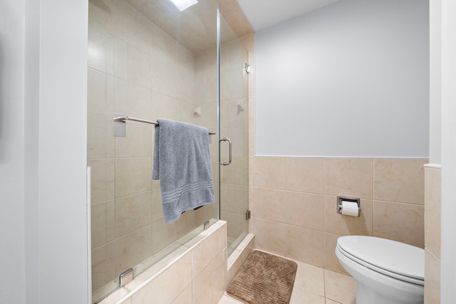 bathroom featuring a stall shower, tile patterned flooring, tile walls, and toilet