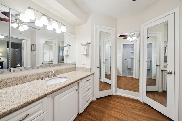 bathroom with ceiling fan, baseboards, wood finished floors, and vanity