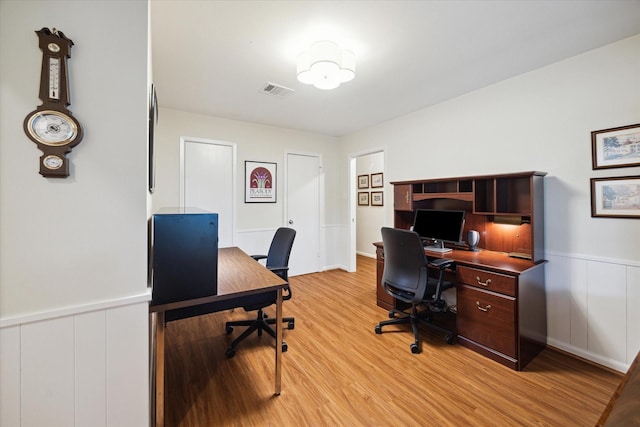 home office featuring light wood-type flooring, visible vents, and wainscoting