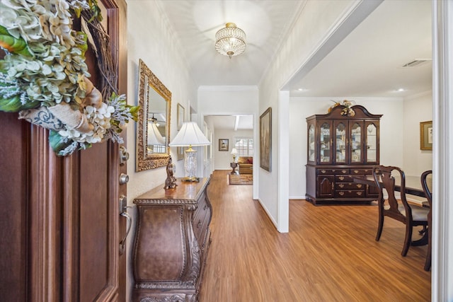 entryway with visible vents, crown molding, baseboards, and wood finished floors